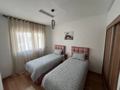 two beds in a room with a window at Cosy Appart au Parc Mohammédia in Mohammedia