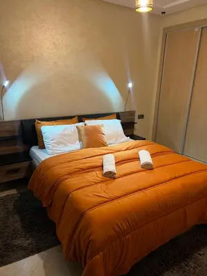 a large orange bed with two towels on it at Cozy appartement avec piscine in Bouznika