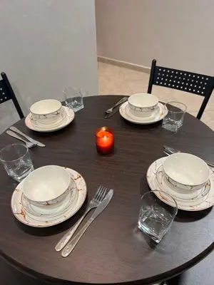 a wooden table with plates and utensils on it at Cozy appartement avec piscine in Bouznika