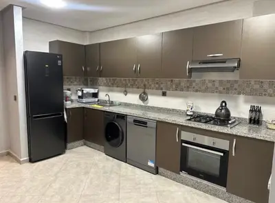 a kitchen with a refrigerator and a dishwasher at Cozy appartement avec piscine in Bouznika