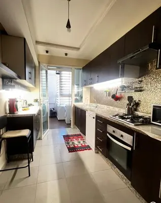 a kitchen with black cabinets and a stove top oven at Family appartment in Casablanca
