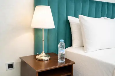 a bottle of water and a lamp on a table next to a bed at Studio Paisible aux Hopitaux Wifi & Parking in Casablanca