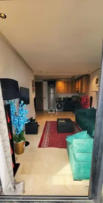 a living room with a couch and a kitchen at Les-iris-Appartement-moderne-chambre-salon-au-cœur-de-Casablanca in Casablanca