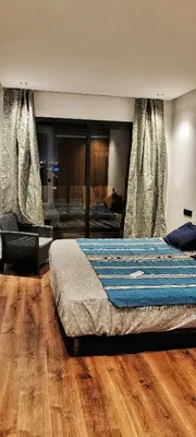 a bedroom with a bed with wooden floors and curtains at Les-iris-Appartement-moderne-chambre-salon-au-cœur-de-Casablanca in Casablanca