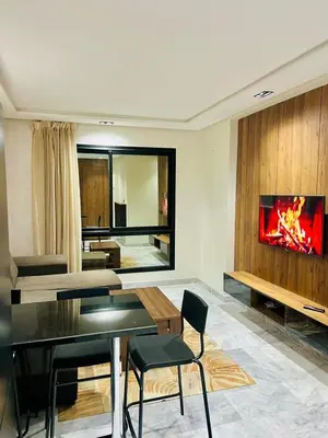 a living room with a table and a tv on a wall at Located at Building 55, Golden Pavilion, 3rd Floor in Casablanca