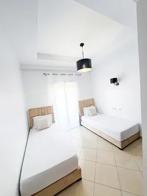 two beds in a room with white walls at Charming 3 bedroom with pool in the building in Casablanca
