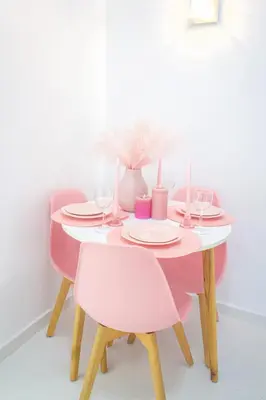 a pink dining room table with two chairs and a table with glasses at Charming 3 bedroom with pool in the building in Casablanca