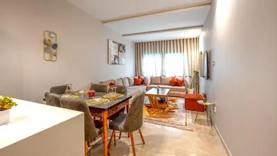 a living room with a table and a couch at L'Amber 1 chambre - 5 min de l'Aéroport- Piscine in Nouaseur