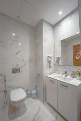a white bathroom with a toilet and a sink at L'Amber 1 chambre - 5 min de l'Aéroport- Piscine in Nouaseur