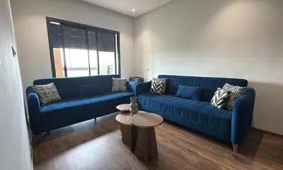 a living room with two blue couches and a table at Appartement Résidence Tamaris Park in Tamaris