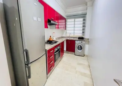 a kitchen with red cabinets and a refrigerator at Familly Residence in Casablanca