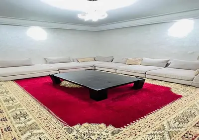 a living room with a couch and a table on a red rug at Familly Residence in Casablanca