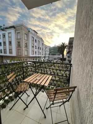 a picnic table and chairs on a balcony with buildings at Central T1 cozy and chic in Rabat