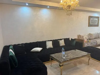 a living room with a black couch and a table at Jolie appartement avec piscine privée in Casablanca