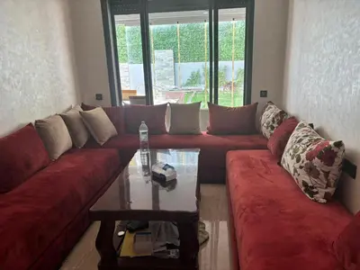 a living room with a red couch and a table at Jolie appartement avec piscine privée in Casablanca