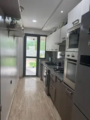a kitchen with white cabinets and a door to a yard at Jolie appartement avec piscine privée in Casablanca