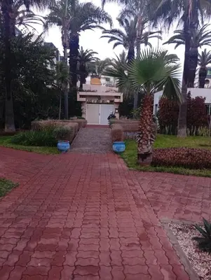 a brick walkway in front of a building with palm trees at Oceania in Mohammedia