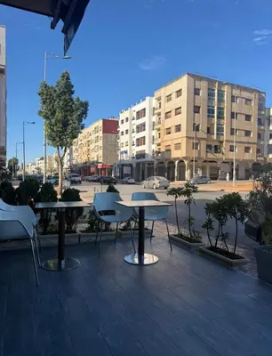 a patio with two tables and chairs and buildings at Nouvel appartement dans le quartier central très agréable à proximité de tous les services in Temara