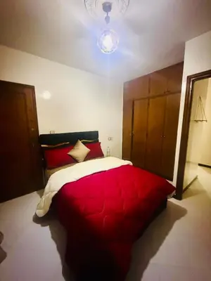 a bedroom with a red and white bed and a chandelier at Nouvel appartement dans le quartier central très agréable à proximité de tous les services in Temara