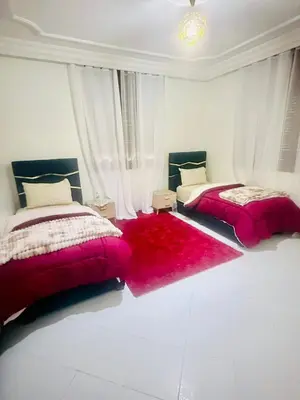 two beds in a white room with red blankets at Nouvel appartement dans le quartier central très agréable à proximité de tous les services in Temara