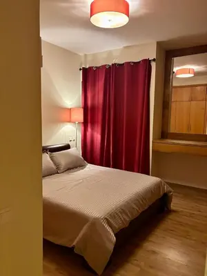 a bedroom with a bed with a red curtain at Appartement lumineux avec parking privé in Temara