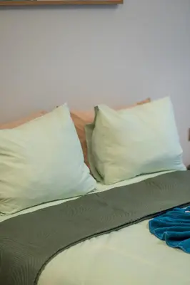 a bed with two pillows and two blankets at Le Rubis - Appartement pour 3 personnes - Avec Piscine - Proche aeroport Mohammed 5 in Nouaseur