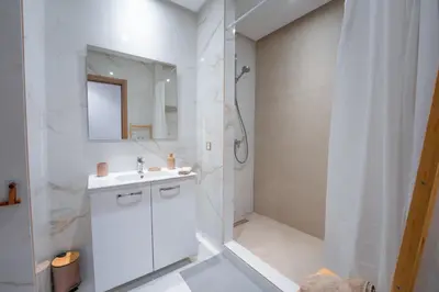 a white bathroom with a sink and a shower at Le Rubis - Appartement pour 3 personnes - Avec Piscine - Proche aeroport Mohammed 5 in Nouaseur