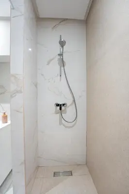 a shower in a bathroom with white marble walls at Le Rubis - Appartement pour 3 personnes - Avec Piscine - Proche aeroport Mohammed 5 in Nouaseur