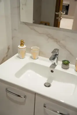 a white bathroom sink with two cups on it at Soleya Apartment with Pool near Mohammed V Airport in Nouaseur