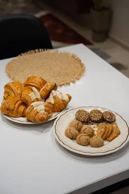 a table with two plates of pastries and a plate of bread at Soleya Apartment with Pool near Mohammed V Airport in Nouaseur