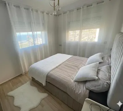 a bedroom with a bed with white walls and windows at Appartement vue sur mer - Chill ocean view in Rabat