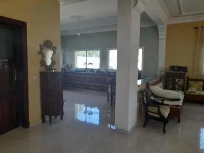 a living room with a pillar and chairs and a table at Bella in Temara