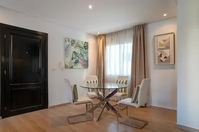 a dining room with a glass table and white chairs at Appartement luxueux &chaleureux au cœur de Rabat in Rabat