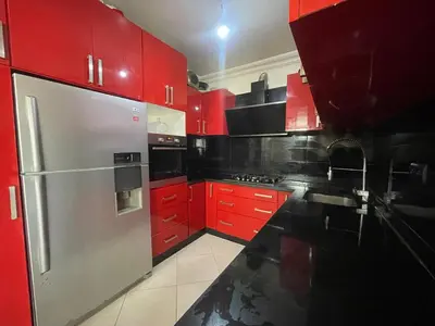 a kitchen with red cabinets and a stainless steel refrigerator at Harhoura Sea view apartment with green spaces and a pool in El Harhoura
