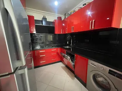 a red kitchen with a washing machine in it at Harhoura Sea view apartment with green spaces and a pool in El Harhoura