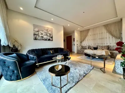 a living room with a blue couch and tables at Appartement Moderne 2 Chambres - Piscine & Parking in Rabat