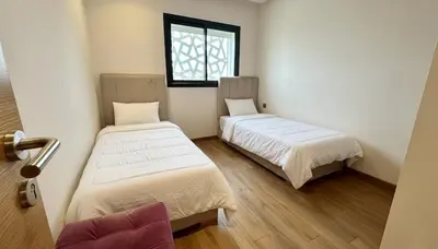 two beds in a small room with a window at Appartement Moderne 2 Chambres - Piscine & Parking in Rabat