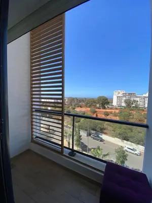 a room with a large window with a view of a street at Appartement Moderne 2 Chambres - Piscine & Parking in Rabat