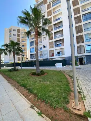two palm trees in a park in front of a building at Appartement Moderne 2 Chambres - Piscine & Parking in Rabat