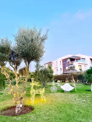 a garden with white chairs and trees and a building at Prestigia Golf City Bouskoura in Bouskoura