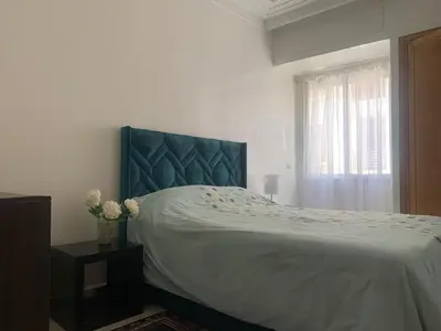 a bedroom with a bed with a blue headboard and a window at Cozy apt in Bourgogne - Ain Diab Coast in Casablanca