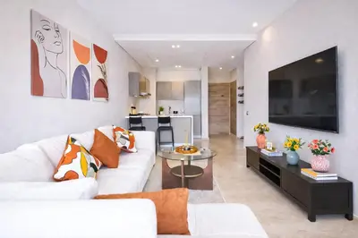 a living room with a white couch and a tv at Modern Cozy Apartment in Prime Location in Nouaceur