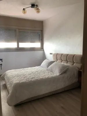 a bedroom with a large bed with two windows at Chez Abir in Rabat