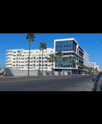a large white building on a city street with palm trees at Magnifique studio disponible sur roche noire in Casablanca