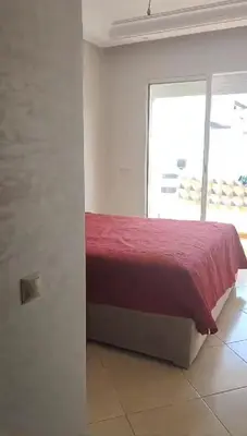 a bed in a white room with a red blanket at Garden Beach in Sidi Rahal