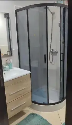 a bathroom with a glass shower with a sink at Garden Beach in Sidi Rahal