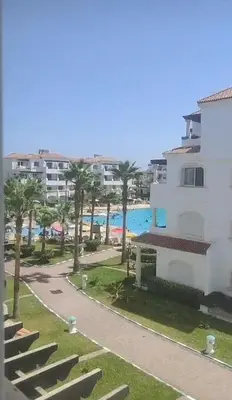 a building with palm trees next to a beach at Garden Beach in Sidi Rahal
