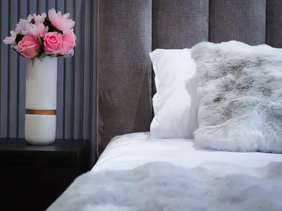 a white vase with pink flowers on a bed at Prestige appartement centre Agdal Rabat in Rabat
