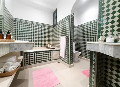 a bathroom with green and white tiles and a tub and toilet at Prestige appartement centre Agdal Rabat in Rabat
