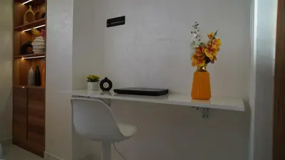 a white desk with a chair and a vase of flowers at Bel appartement, piscine intérieure et extérieure in Temara
